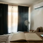 Rutina eficiente de aire acondicionado en recámara con ventilador, cortinas para sombra y mini split funcionando